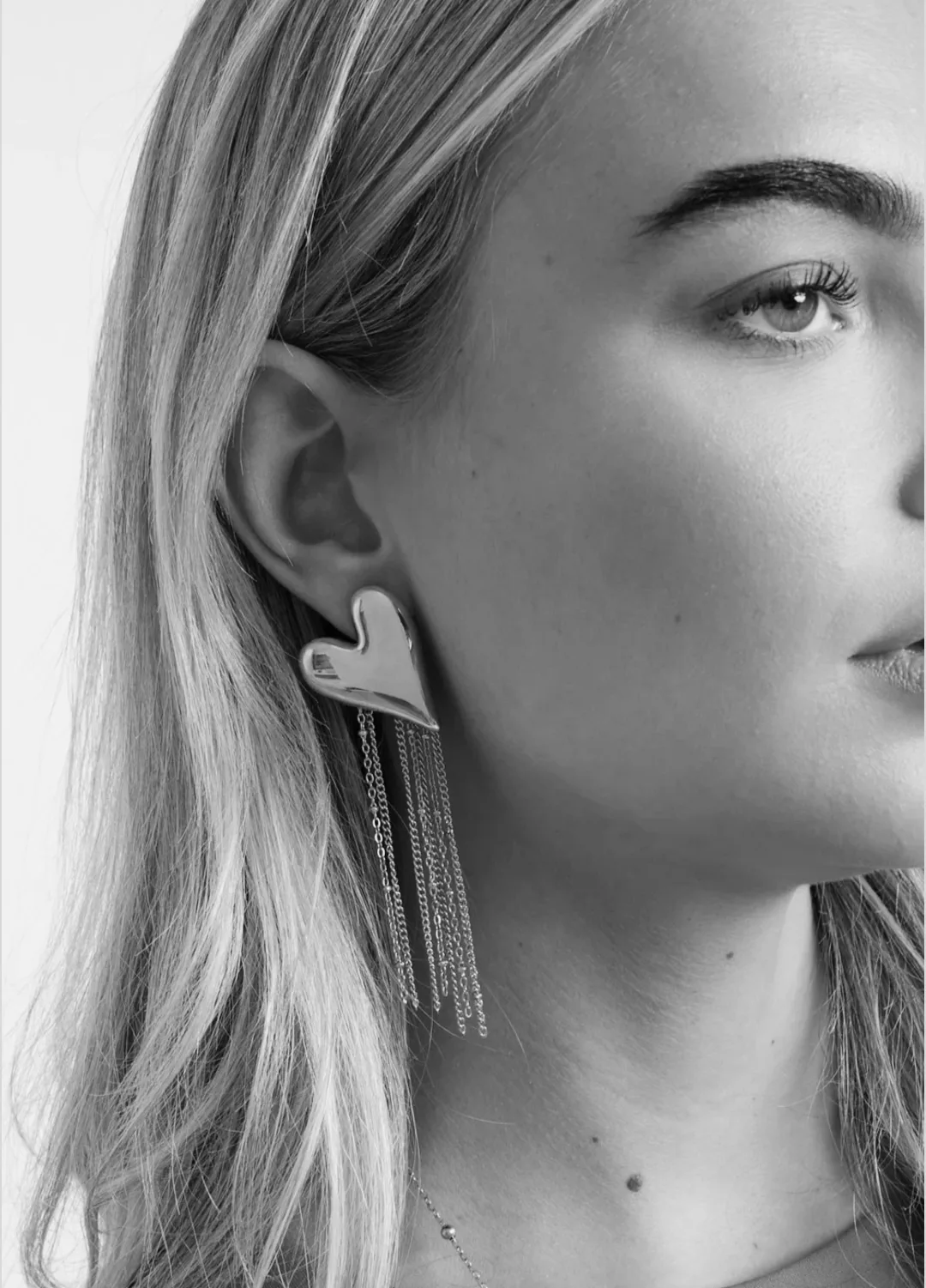 By Jeanny Heart Earrings – Christmas Edition; goudkleurige stainless-steel oorbellen met glanzend hart en fijne kettingdetails, feestelijke damesoorbellen voor de kerstcollectie.