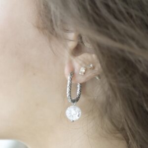 Close-up cracked bergkristal steen met lichtreflectie aan stainless steel oorring – By Jeanny